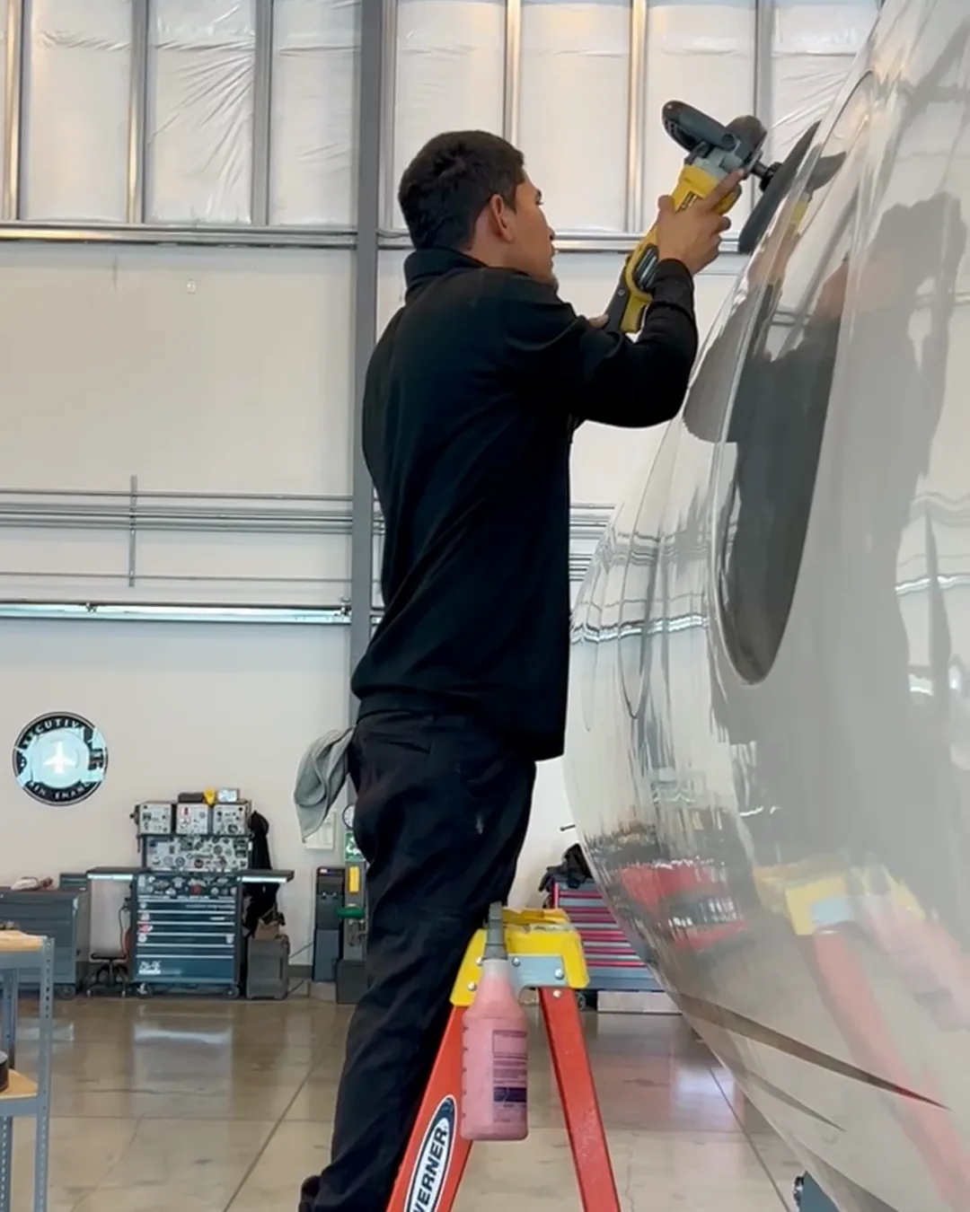 Joel polishing a mirror finish aluminum fuselage inside a bright hangar